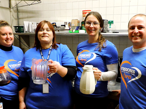 Visions staff smile with pitchers of coffee, water, and tea at American Legion Post 1645 for Clear Path's Thanksgiving Canteen Luncheon.