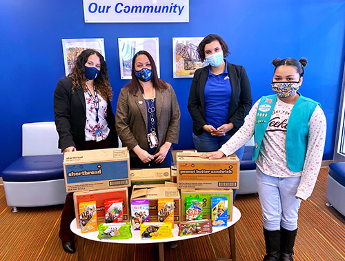 The Reading, PA Impact and Engagement team poses with a table filled with Girl Scout Cookies purchased to donate to frontline healthcare workers.
