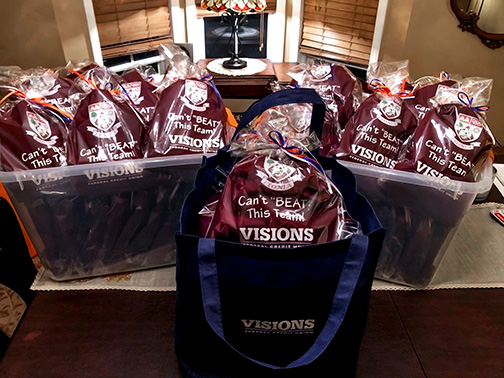 75 custom aprons are pictured on display that will be indly donated to Leonia High School's Culinary Arts Program students. They all have a design with the Visions logo, and the witty statement, “Can't Beat This Team!”