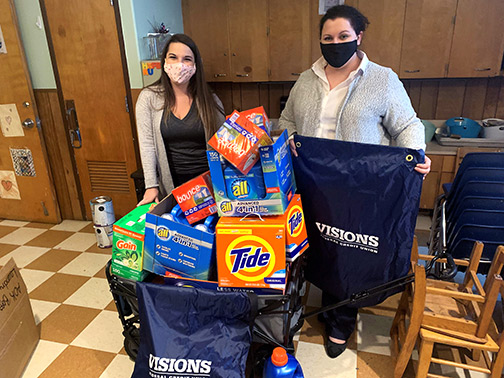 Visions Community Development department members, Samantha and Jocelyn, show off a wagon filled with Visions branded laundry bags and detergent that we donated to the Neighborhood Transformation Center in Elmira, NY.