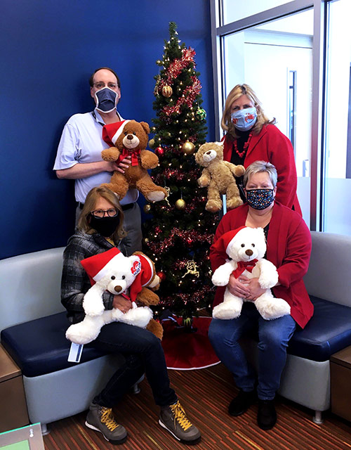 Visions FCU staff pose in front of a holiday tree with stuffed teddy bears. These bears were donated to the Reading Royals in PA as a way to give back to those in need in the community.