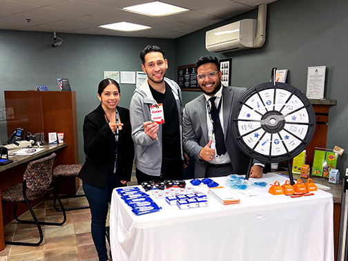 Community Development Liaison, Gustavo, and staff at our GIANT in-store branch in PA give a thumbs up from the Visions table filled with giveaways and a prize wheel.