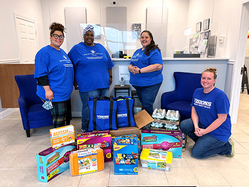 Visions Marketing Program Administrator, Lindsay, and advocates from the Special Parent Advocacy Group stand and smile with donated items.