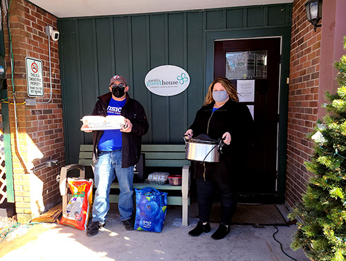 Our Syracuse, NY stand in front of Sarah's Guest House with homemade meals for residents to celebrate the Super Bowl!