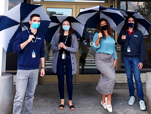 Visions employees pose outside a local branch with umbrellas to be passed out for free to members on rainy days.