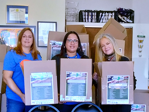Visions employees Mary, Nikisha, and Elizabeth posing with care boxes assembled for veterans and their families.