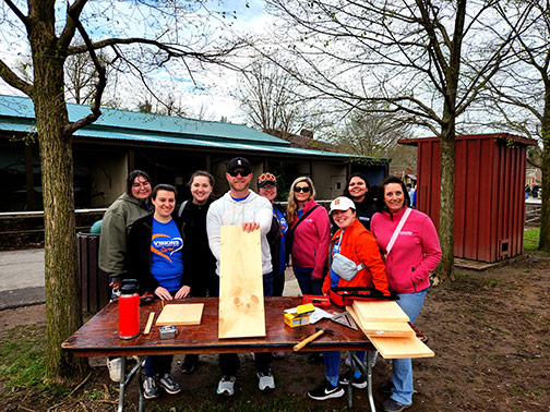 The Visions volunteer team proudly posing with a birdhouse that is under construction.