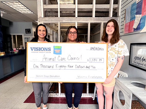 Visions representatives, Emily and Megan, and a nurse from the Animal Care Council smile with a large check that contains a donation to the Animal Care Council.