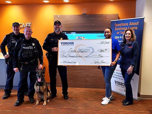 Irondequoit and City of Rochester Police officers pictured in the lobby of our Rochester branch posing with a large check.