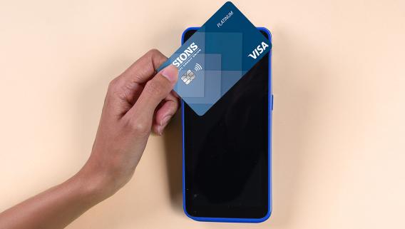 person tapping their Visions Visa Platinum credit card to their cell phone