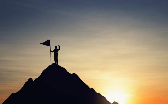 man on top of a mountain with a flag