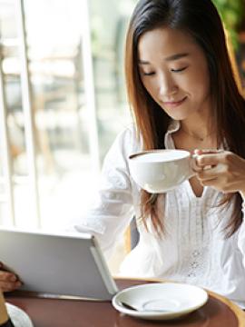 woman reading on computer and drinking coffee
